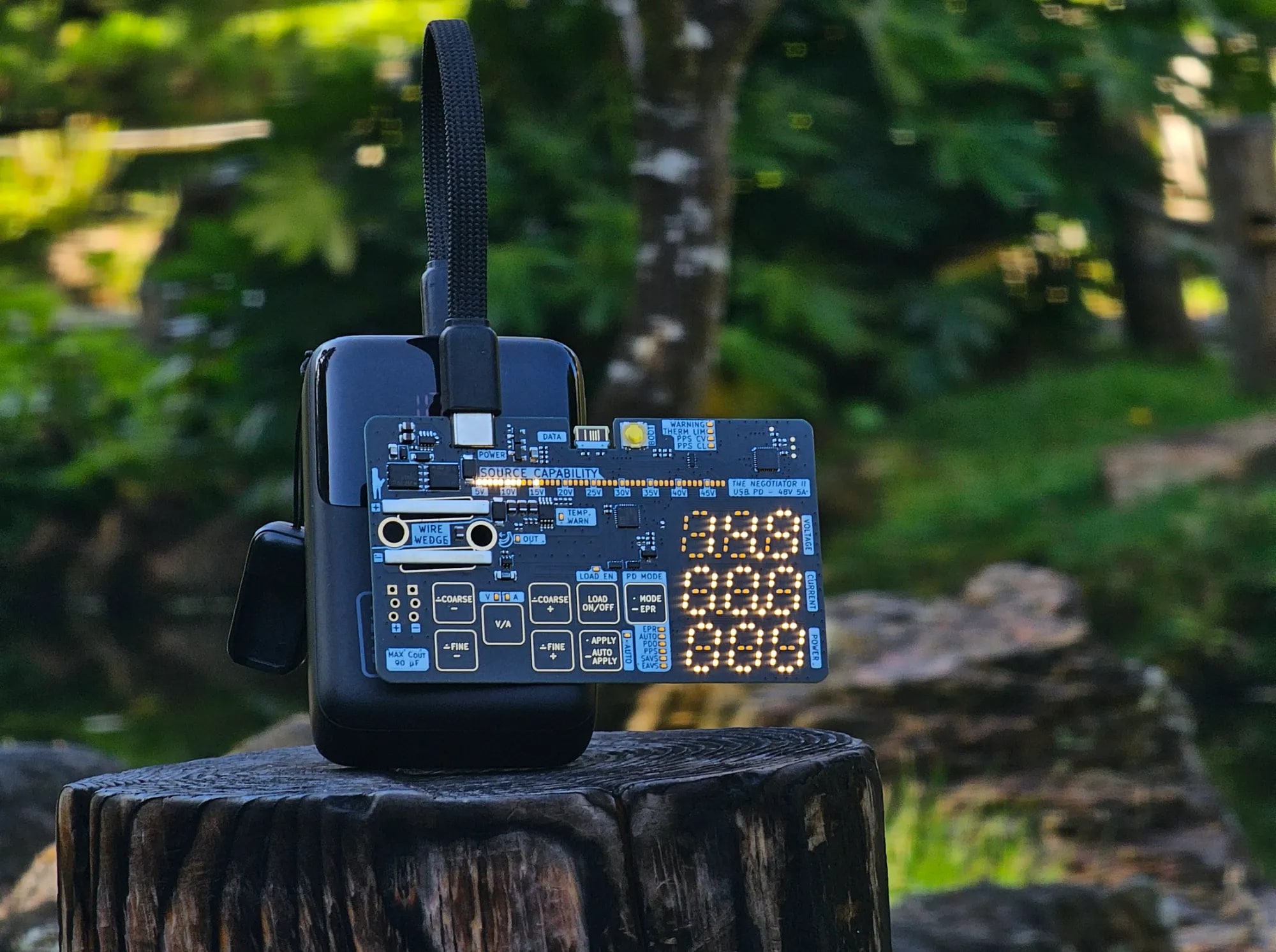 The Negotiator II business card powered from a power bank, with its source capability bar and displays lit